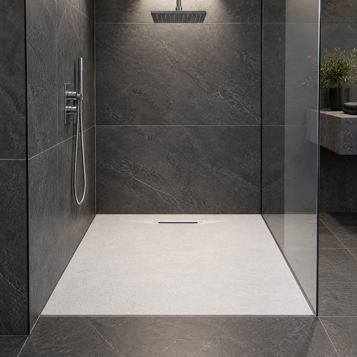 Duschwanne in weißer Steinoptik, bodeneben eingebaut in einer Dusche mit anthrazitfarbenen Fliesen und Glaswand